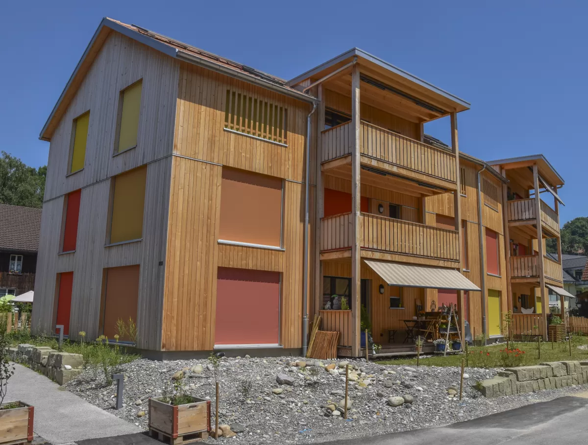 Mehrfamilienhaus in Lyss. Das Haus ist von einem Naturgarten umschlungen. Die Storen sind nach einem Farbmuster von der Bauherrin ausgewählt.