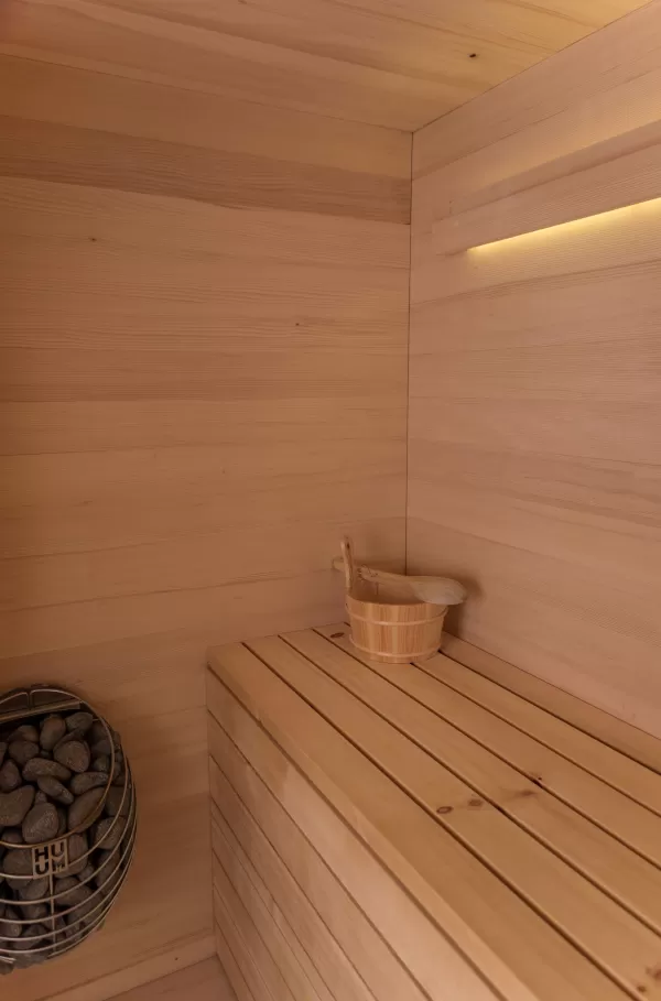 Truberholz Mehrfamilienhaus. Aussenschalung vor vergrautes Falzbrett aus Tanne, integrierte Sauna in Ferienwohnung, Saunawand aus Tanne, Möbel in der Saune aus Arven Holz, Truberholz-Wände innen sichtbar, inklusive Decke Dachschräge, Gebäudehülle Truberholz sichtbar, Innendecke Brettstapel, Boden ist alles Trockenbauaufbau, Zimmer und Bad aus Tannen Holz und allgemein Räume sind Buchenriemenboden. Türen sind alle Massivholz mit Blockfutter aus Tanne.