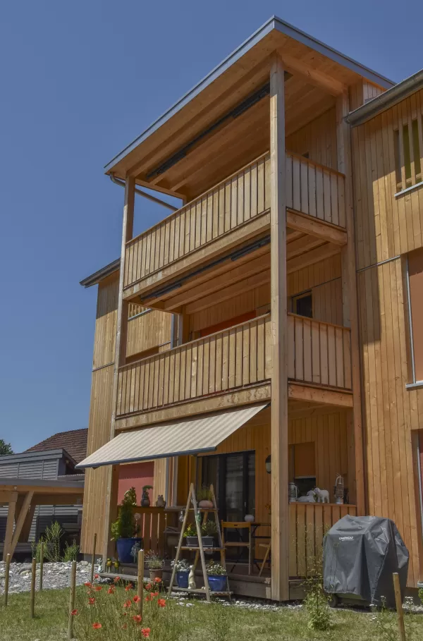 Mehrfamilienhaus in Lyss. Das Haus ist von einem Naturgarten umschlungen. Die Storen sind nach einem Farbmuster von der Bauherrin ausgewählt.