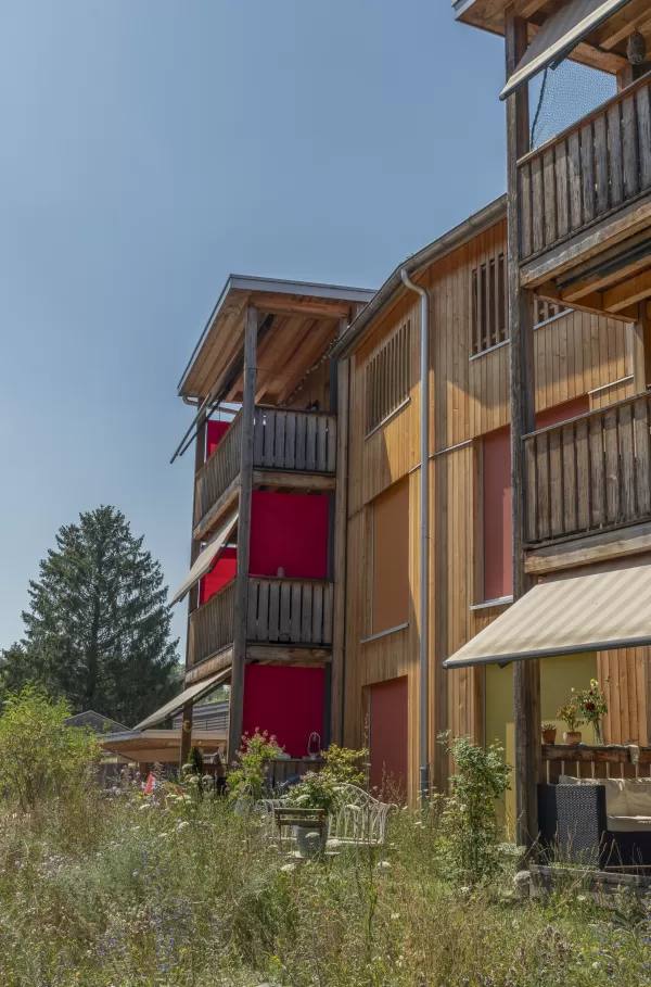 Mehrfamilienhaus in Lyss. Das Haus ist von einem Naturgarten umschlungen. Die Storen sind nach einem Farbmuster von der Bauherrin ausgewählt.