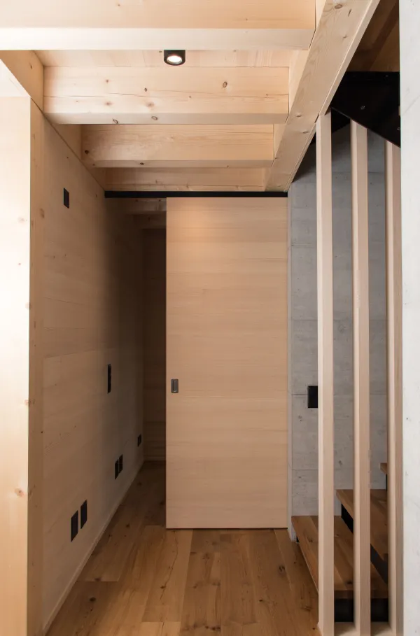 Innenansicht eines modernen Holzbaus mit sichtbaren Balken, natürlichen Holzoberflächen und massgefertigten Einbauten. Grosszügige Fensterflächen sorgen für viel Tageslicht und unterstreichen die warme, ruhige Wohnatmosphäre. Hochwertige Materialien und präzise Schreinerarbeiten prägen das Gesamtbild.