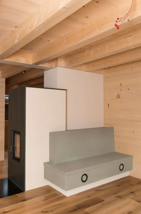 Innenansicht eines modernen Holzbaus mit sichtbaren Balken, natürlichen Holzoberflächen und massgefertigten Einbauten. Grosszügige Fensterflächen sorgen für viel Tageslicht und unterstreichen die warme, ruhige Wohnatmosphäre. Hochwertige Materialien und präzise Schreinerarbeiten prägen das Gesamtbild.