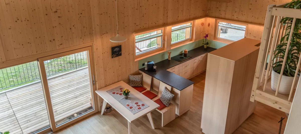 Innenausbau Truberholz, Blick von der Galerie in die Küche und Wohnbereich. Nach oben alles offen mit Oberlichtfenster. Im Wohnbereich Fensterreihe bei der Küche.