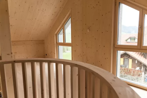 Truberholz Mehrfamilienhaus. Aussenschalung vor vergrautes Falzbrett aus Tanne, integrierte Sauna in Ferienwohnung, Saunawand aus Tanne, Möbel in der Saune aus Arven Holz, Truberholz-Wände innen sichtbar, inklusive Decke Dachschräge, Gebäudehülle Truberholz sichtbar, Innendecke Brettstapel, Boden ist alles Trockenbauaufbau, Zimmer und Bad aus Tannen Holz und allgemein Räume sind Buchenriemenboden. Türen sind alle Massivholz mit Blockfutter aus Tanne.