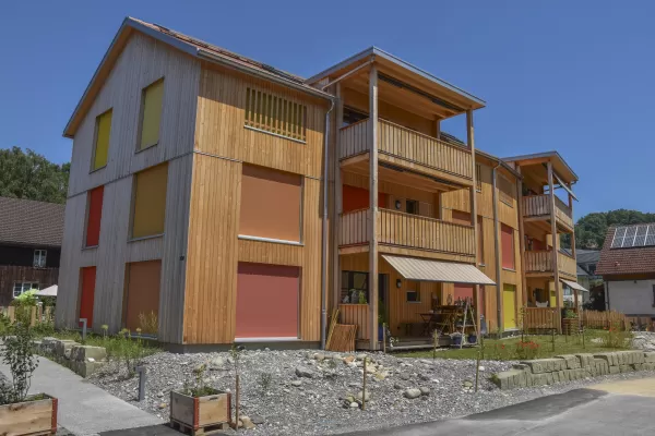 Mehrfamilienhaus in Lyss. Das Haus ist von einem Naturgarten umschlungen. Die Storen sind nach einem Farbmuster von der Bauherrin ausgewählt.