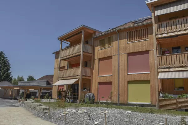 Mehrfamilienhaus in Lyss. Das Haus ist von einem Naturgarten umschlungen. Die Storen sind nach einem Farbmuster von der Bauherrin ausgewählt.